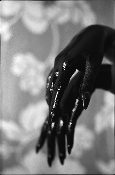 Black and white photograph of a pair of hands, wet and glittering, against a soft blurred ground.