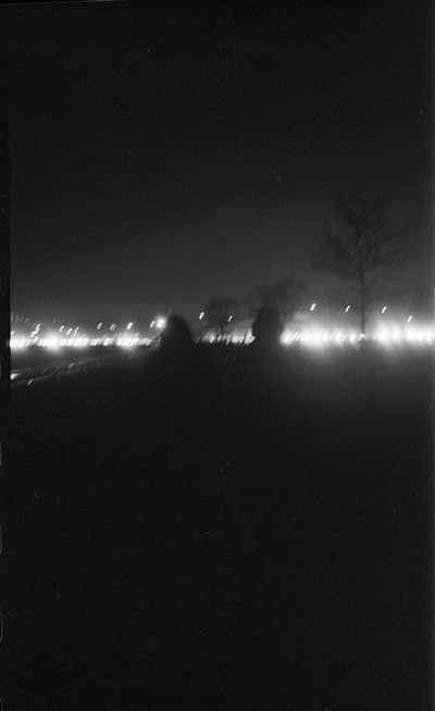 Near-black night photograph, a low band of distant lights across the horizon.